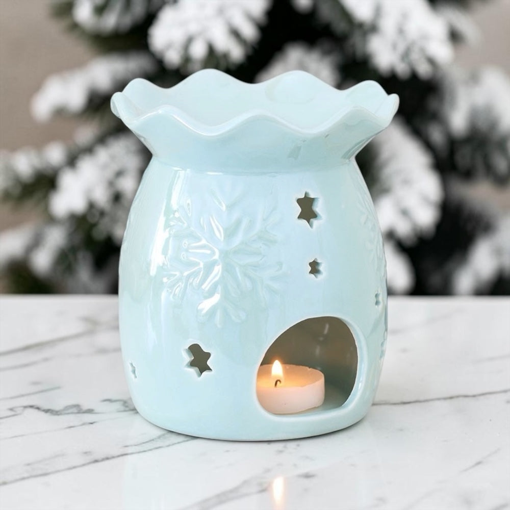 Lichtblauwe keramische waxbrander met sneeuwvlok reliëf en iriserende glans met brandend waxinelichtje