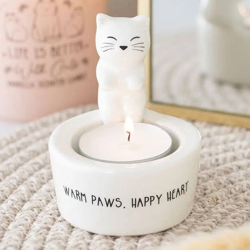 Witte keramische theelichthouder met een 3D katje en de tekst Warm Paws, Happy Heart waarin een waxinelichtje brandt