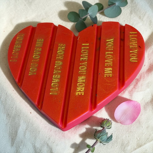 Een gedetailleerde foto van het Macey's Candles Roos & Eucalyptus 'Breek-Mijn-Hart' waxmelt product, uitgepakt op een linnen doek. De rode sojawas is direct voorzien van de gouden teksten 'I LOVE YOU', 'YOU LOVE ME', 'I LOVE YOU MORE'.