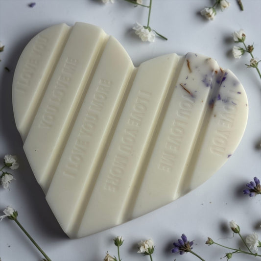 Handgemaakte witte hartvormige waxmelt 'Heavenly White Musk' van Macey's Candles in een kraft doosje. De was bevat paarde bloemblaadjes en glitters.